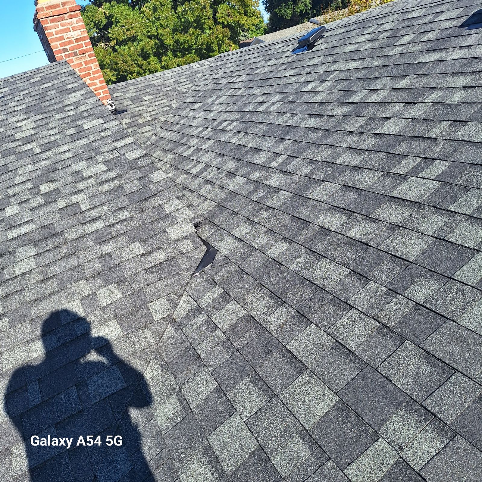 Repaired shingle section near a brick chimney